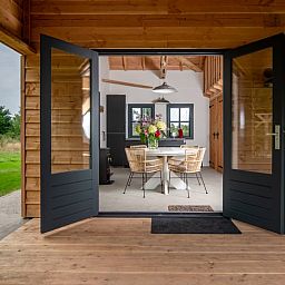 Gezellige binnenruimte van Vakantiehuis in Empe, Gelderse vallei, met open deuren naar terras en uitzicht op de natuur.