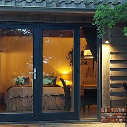 Gezellige slaapkamer van Huisje in Tonden, vakantiehuis in de Gelderse vallei, met warme verlichting en uitzicht op de natuur.