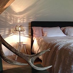 Sfeervolle slaapkamer in Huisje in Kootwijk, Veluwe, met comfortabel bed en rustieke details.