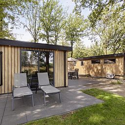 Terras van Module Wood 5 personen vakantieaccommodatie in Ede Veluwe met ligstoelen en groene omgeving.