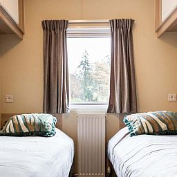 Zweites Schlafzimmer im Ferienhaus in Ede, Veluwe, Gelderland mit Blick auf ein Waldgebiet.