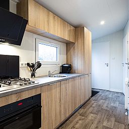 Stylish kitchen in Luna vacation home, Ede, Veluwe, with wooden cabinets and appliances.
