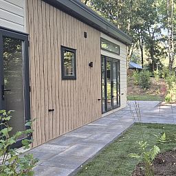 Seitenansicht des Ferienhauses Module Nova in Ede, Veluwe mit Terrasse und umliegender Natur.