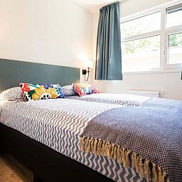 Slaapkamer in Module Special 4 personen Wellness te Ede, Veluwe met comfortabel tweepersoonsbed en kleurrijke kussens.