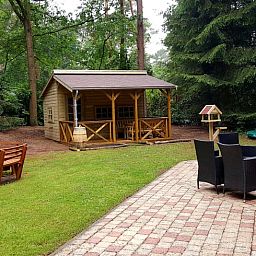 Wooden gazebo at cottage in Emst, Veluwe, surrounded by trees.