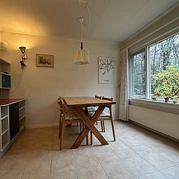 Gemuetliche Essecke im Ferienhaus in Emst, Veluwe, mit Blick auf die gruene Natur von Gelderland.