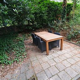 Aussenterrasse im Ferienhaus in Ermelo, Veluwe, umgeben von gruener Natur.