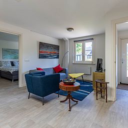 Ingang van vakantiehuis DG1560 in Ermelo, Veluwe, Gelderland, omgeven door groene hagen en schaduwrijke bomen.