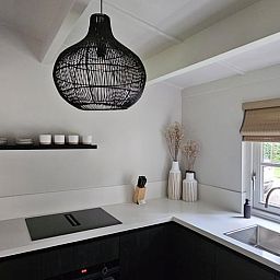 Stilvolle Kueche im Ferienhaus in Ermelo, Veluwe, Gelderland mit moderner Einrichtung und natuerlichem Licht durch das Fenster.