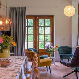 Gezellige woonkamer in Huisje in Ermelo, Veluwe, met kleurrijke stoelen en uitzicht op de natuur in Gelderland.