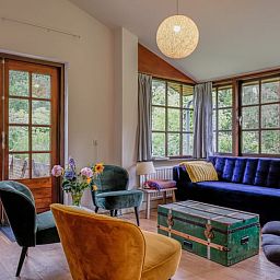 Gezellige woonkamer van Huisje in Ermelo, vakantiehuis op de Veluwe, Gelderland, met uitzicht op de groene natuur door grote ramen.
