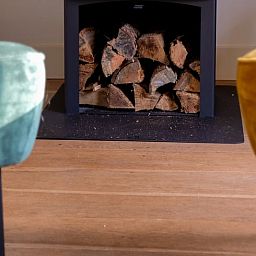 Gezellige binnenruimte van Huisje in Ermelo op de Veluwe, Gelderland, met een sfeervolle open haard en comfortabele stoelen.