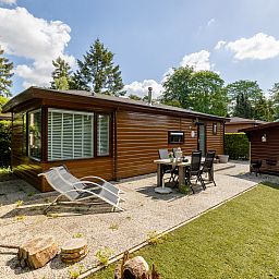 Gemuetliche Terrasse am Ferienhaus Tiny Lodge in Harderwijk, Veluwe, Gelderland mit Liegestuehlen und Esstisch.