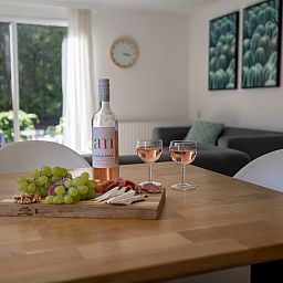 Gemuetlicher Essbereich im Ferienhaus Tiny Lodge in Harderwijk, Veluwe, Gelderland mit Wein und Snacks.