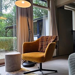 Gezellige binnenruimte van Vakantiehuis in Hoenderloo op de Veluwe, met comfortabele stoel en uitzicht op groene omgeving in Gelderland.