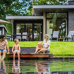 Family enjoys the pond at Holiday home Deerhoeve comfort in Hoenderloo, Veluwe. Perfect for relaxation and nature.