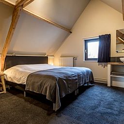 Sfeervolle slaapkamer in Huisje in Hoenderloo, Veluwe, met rustieke elementen.