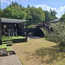 Veranda of Chalet Relax in Putten, Veluwe, Gelderland, surrounded by green nature, ideal for a relaxing vacation stay.