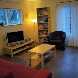 Gemuetliches Wohnzimmer im Ferienhaus in Putten, Veluwe, Gelderland mit komfortabler Sitzecke und Blick auf die natuerliche Umgebung.