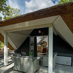 Geniessen Sie die Ruhe auf der Veranda des Huisje in Putten, einem charmanten Ferienhaus in Veluwe, Gelderland, umgeben von Natur.