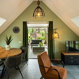 Gemuetliches Wohnzimmer des Huisje in Putten, Ferienhaus an der Veluwe in Gelderland, mit Blick auf den gruenen Garten und moderner Einrichtung.