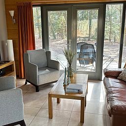 Gemuetliches Wohnzimmer im Ferienhaus in Voorthuizen mit Blick auf die Waelder der Veluwe.