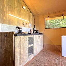 Gezellige keuken in tenthuis Libelle, Hulshorst, Veluwe. Geniet van een knusse glamping ervaring met uitzicht op de omliggende natuur.