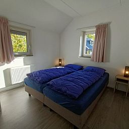Slaapkamer met tweepersoonsbed in Vakantiehuis Geheim van Otterlo 6 in Otterlo, Veluwe, Gelderland.