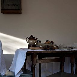 Gemuetliche Essecke im Ferienhaus in Otterlo, Veluwe, Gelderland, mit rustikalem Tisch und warmer Atmosphaere fuer einen entspannten Aufenthalt.