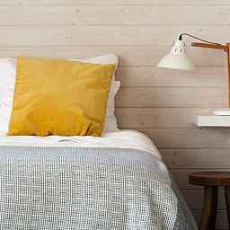 Gemuetliches Schlafzimmer im Ferienhaus in Epe, Veluwe. Bequemes Bett mit hoelzernem Wanddekor und stimmungsvoller Beleuchtung in Gelderland.