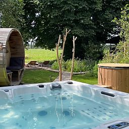 Entspannen Sie sich im Whirlpool des Ferienhauses in Scherpenzeel, Gelderland, mit Blick auf die gruene Veluwe-Landschaft.