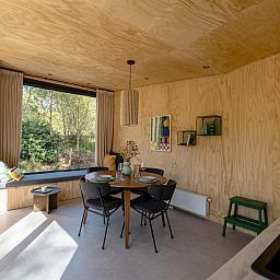 Gezellige binnenruimte van vakantiehuis Mos in Nunspeet, Veluwe met houten interieur en uitzicht op de natuur van Gelderland.