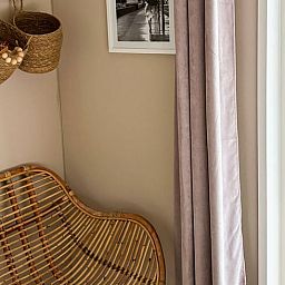 Stilvolle Ecke mit Rattanstuhl im Ferienhaus in Nunspeet, Veluwe, Gelderland, perfekt fuer Entspannung und Naturerlebnis.