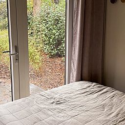 Blick aus dem Schlafzimmer im Ferienhaus in Nunspeet, Veluwe, Gelderland, mit ruhigem Garten und natuerlicher Umgebung fuer ultimative Entspannung.