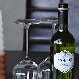 Weinflasche und Glaeser auf dem Tisch im Ferienhaus in Lunteren, Veluwe, Gelderland.