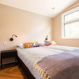 Schlafzimmer mit Doppelbett in Silva 5 Personen Wellness-Ferienhaus, Lunteren, Veluwe, mit natuerlichem Licht und komfortabler Einrichtung.