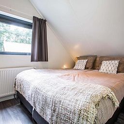 Gemuetliches Schlafzimmer in der Recreation Villa 6 Personen Wellness, Lunteren, Veluwe. Komfortables Doppelbett mit Blick auf die Natur.