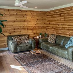 Cozy living room in Cottage in Lunteren, Veluwe, with wooden walls and comfortable sofas.