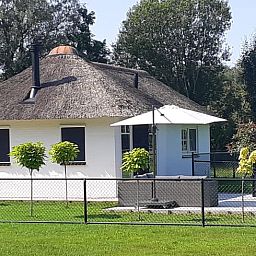 Rueckansicht des Ferienhauses in Heerde mit Terrasse und geschlossenem Garten in Gelderland.