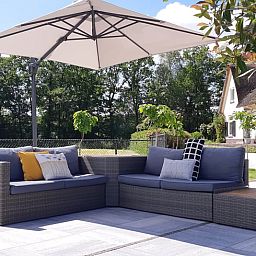 Geraeumige Sitzecke auf der Terrasse des Ferienhauses in Heerde, umgeben von Natur in der Veluwe.