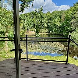 Terrasse des Ferienhauses in Hattem mit schoener Aussicht auf Teich und Wald in Veluwe, Gelderland.