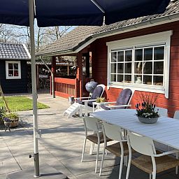 Sunny terrace with dining table at Boshuis Denne, vacation home in Bennekom, Veluwe, Gelderland for outdoor meals.