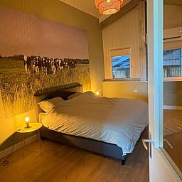 Attractive bedroom in Holiday cottage in Schildwolde, northeastern Groningen, with comfortable bed and country mural.