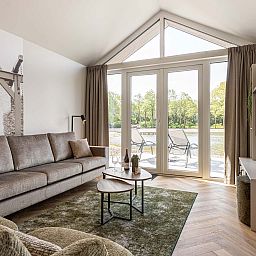 Cozy living room of the detached house in Sellingen, Groningen, with views of nature through large windows and a comfortable seating area.