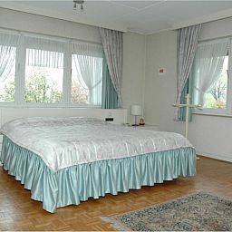 Gerumiges Schlafzimmer mit groem Bett in der Ferienvilla Hubertushof, Horst, Nord-Limburg, mit viel Tageslicht und eleganten Vorhngen.
