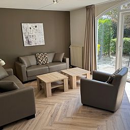 Gemuetliches Wohnzimmer der Comfort Villa 6 in Arcen, Nordlimburg, mit bequemen Sitzgelegenheiten und Blick auf den gruenen Garten.