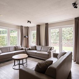 Gezellige woonkamer in de Vrijstaande woning in Arcen, Noord Limburg, met comfortabele banken en uitzicht op de groene tuin.