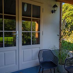 Gezellige veranda van Vakantiehuis in Griendtsveen, Noord Limburg, met uitzicht op groene natuur en comfortabele zitjes.