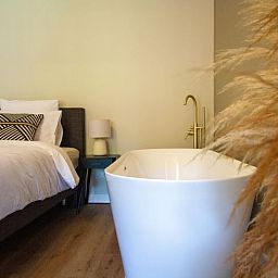 Luxe slaapkamer met vrijstaand bad in Vakantiehuis in Griendtsveen, Noord Limburg. Geniet van comfort en rust in deze sfeervolle vakantiewoning.