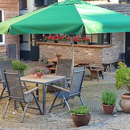 Sonnige Terrasse mit Sonnenschirm im Ferienhaus in Valkenburg aan de Geul, Suedlimburg.